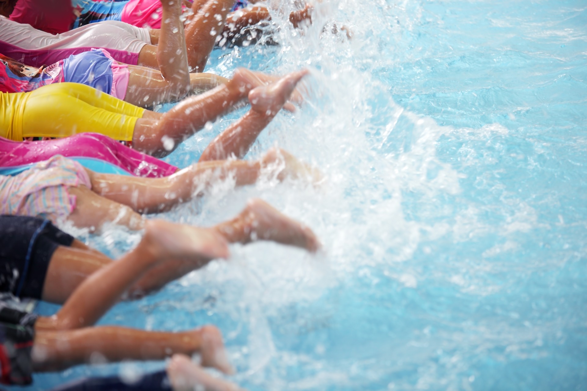 Children in swimming lesson kicking