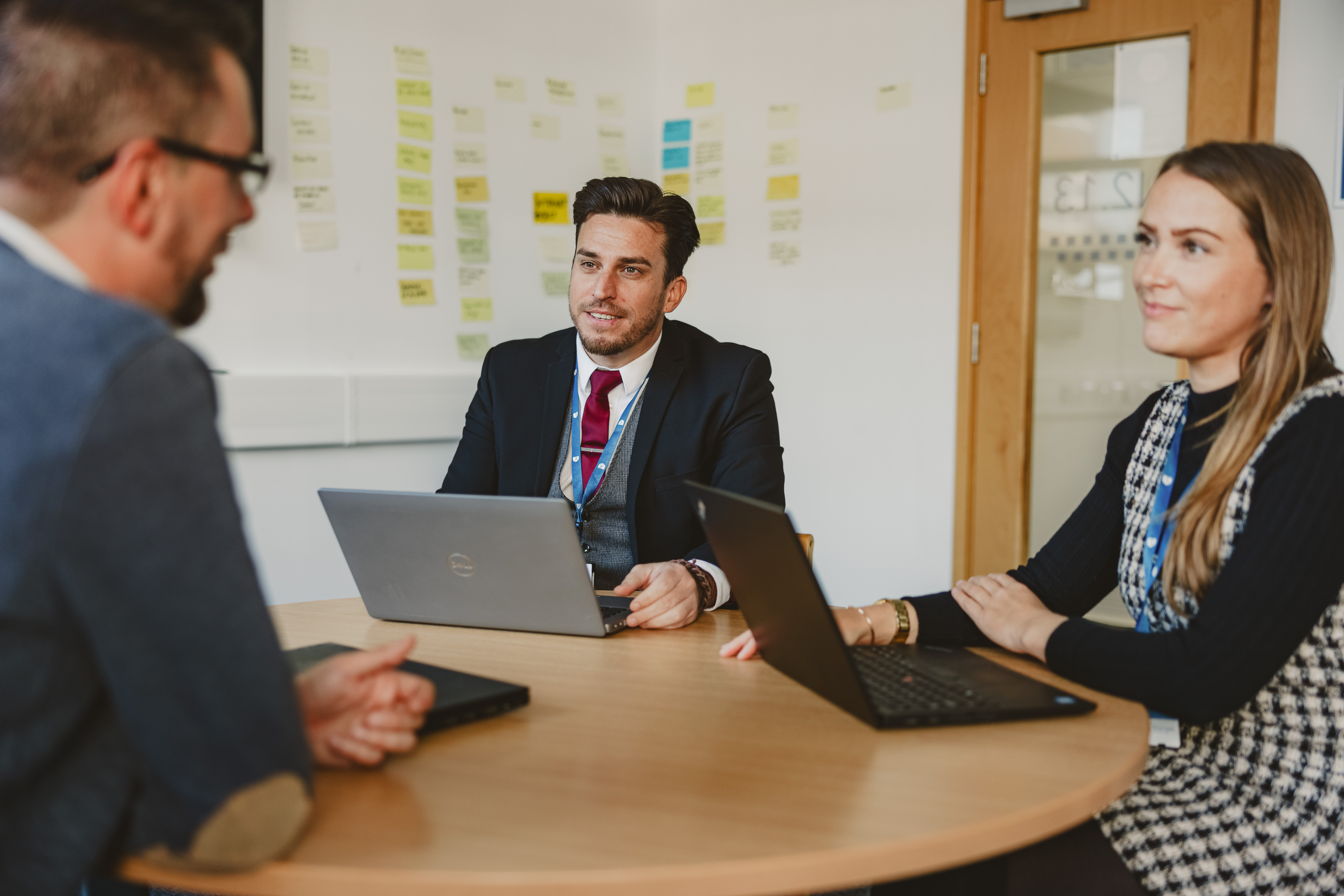 Three people in the meeting room, sitting around the table and talking.