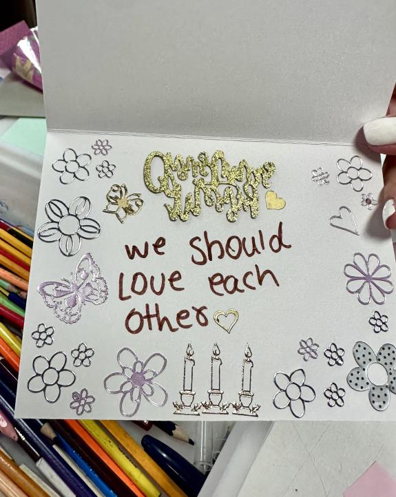 art from a refugee child, a card saying we should love each other with drawings of candles and hearts